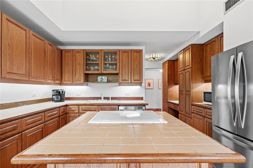 A kitchen features oak cabinets, a tiled island countertop, and stainless steel appliances — 32 GREEN VILLAS DRIVE UNIT 32, DORADO, PR
