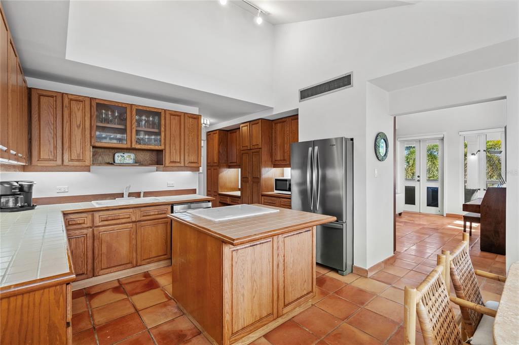 A kitchen with oak cabinets, a tiled island, and stainless steel appliances on terracotta floors — 32 GREEN VILLAS DRIVE UNIT 32, DORADO, PR