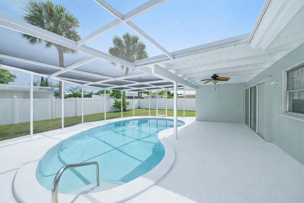 A screened-in patio features a kidney-shaped swimming pool and a white ceiling fan — 2534 WANETA DRIVE, SARASOTA, FL