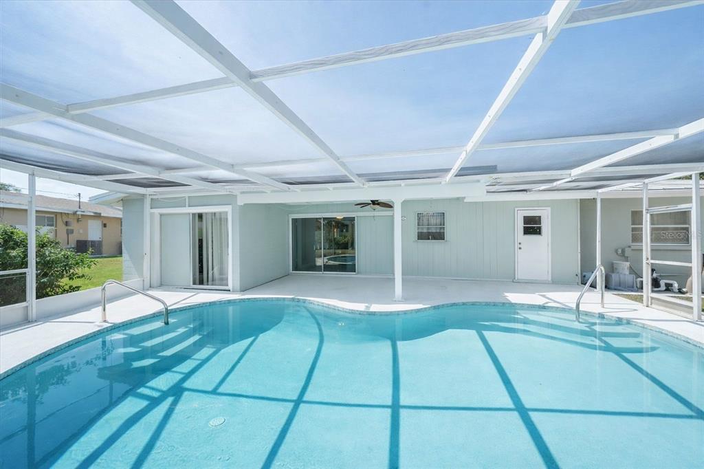 A screened-in patio features a swimming pool with steps and a white concrete deck — 2534 WANETA DRIVE, SARASOTA, FL