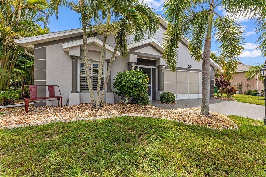 A single-story house with a gray exterior, a front porch, and a gravel landscaping bed — 1812 BIRMINGHAM BOULEVARD, PORT CHARLOTTE, FL