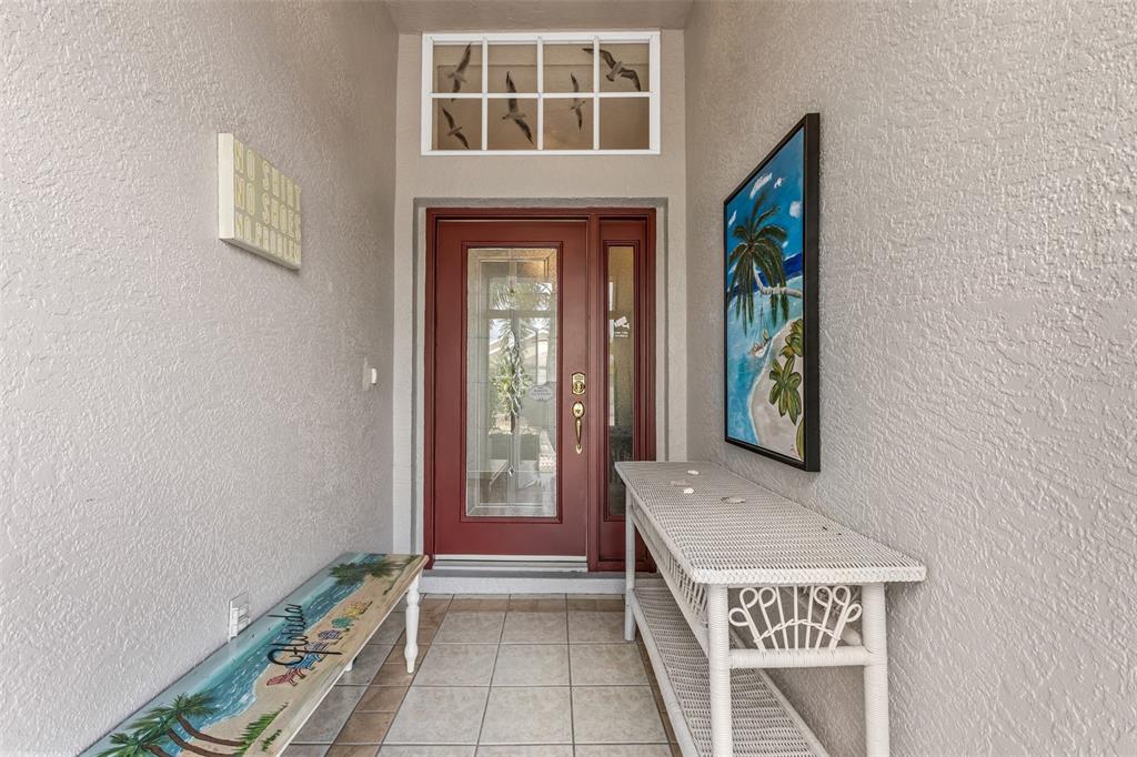 An entryway features a red front door, a tiled floor, a bench, and a console table — 1812 BIRMINGHAM BOULEVARD, PORT CHARLOTTE, FL