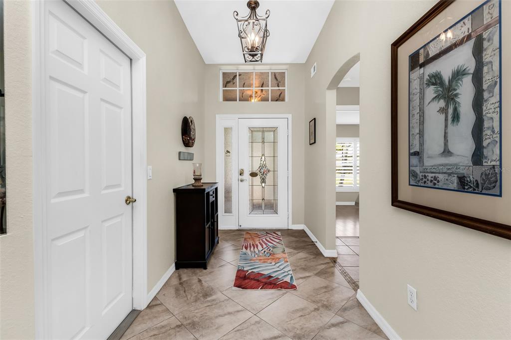 An entryway with tiled floors, a decorative front door, and a hanging light fixture — 1812 BIRMINGHAM BOULEVARD, PORT CHARLOTTE, FL