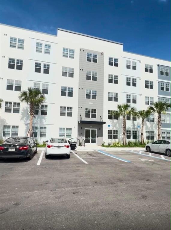 A multi-story apartment building with a white facade and a grey central entrance section — 5587 MILLENIA PARK BOULEVARD UNIT 518, ORLANDO, FL