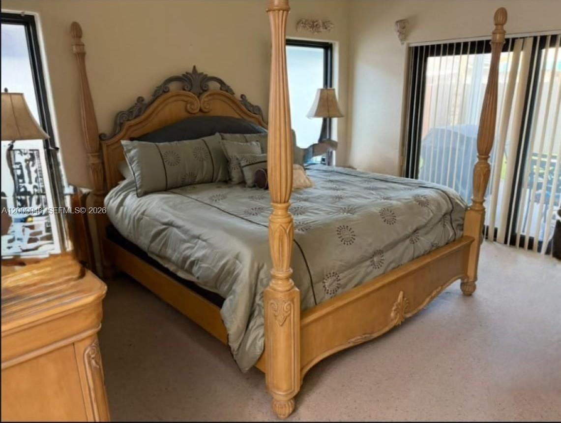 A bedroom features a large wooden four-poster bed with a light green patterned comforter — 8741 NW 141st Ter, Miami Lakes FL 33018, MIAMI LAKES, FL