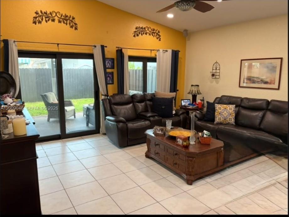A living room with tile floors, dark leather sofas, and sliding glass doors to a patio — 8741 NW 141st Ter, Miami Lakes FL 33018, MIAMI LAKES, FL