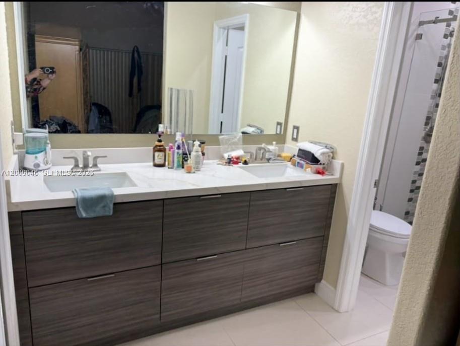 A bathroom features a double-sink vanity with dark wood cabinets and a large wall mirror — 8741 NW 141st Ter, Miami Lakes FL 33018, MIAMI LAKES, FL