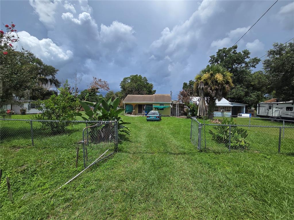 A yellow house with a fenced yard, a parked car, and a travel trailer — 2714 SAMPLE STREET, KISSIMMEE, FL