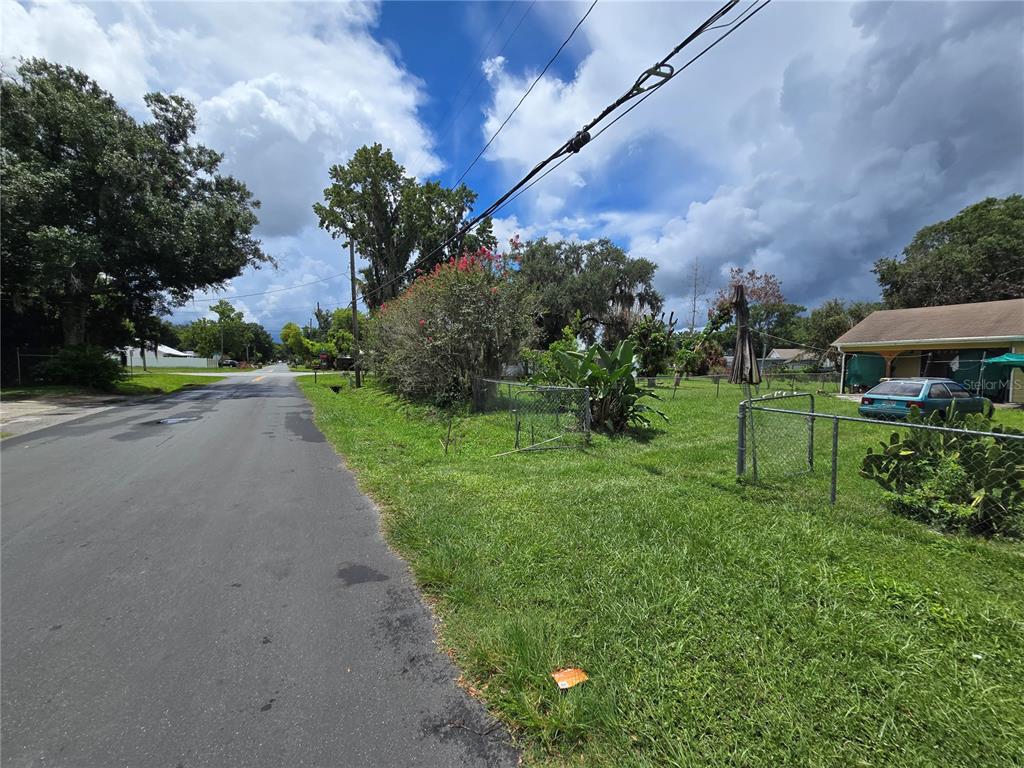 A paved road runs alongside a grassy lot with a chain-link fence and house — 2714 SAMPLE STREET, KISSIMMEE, FL