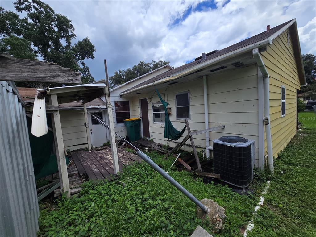 The exterior of a yellow house features a weathered wooden deck and an air conditioning unit — 2714 SAMPLE STREET, KISSIMMEE, FL