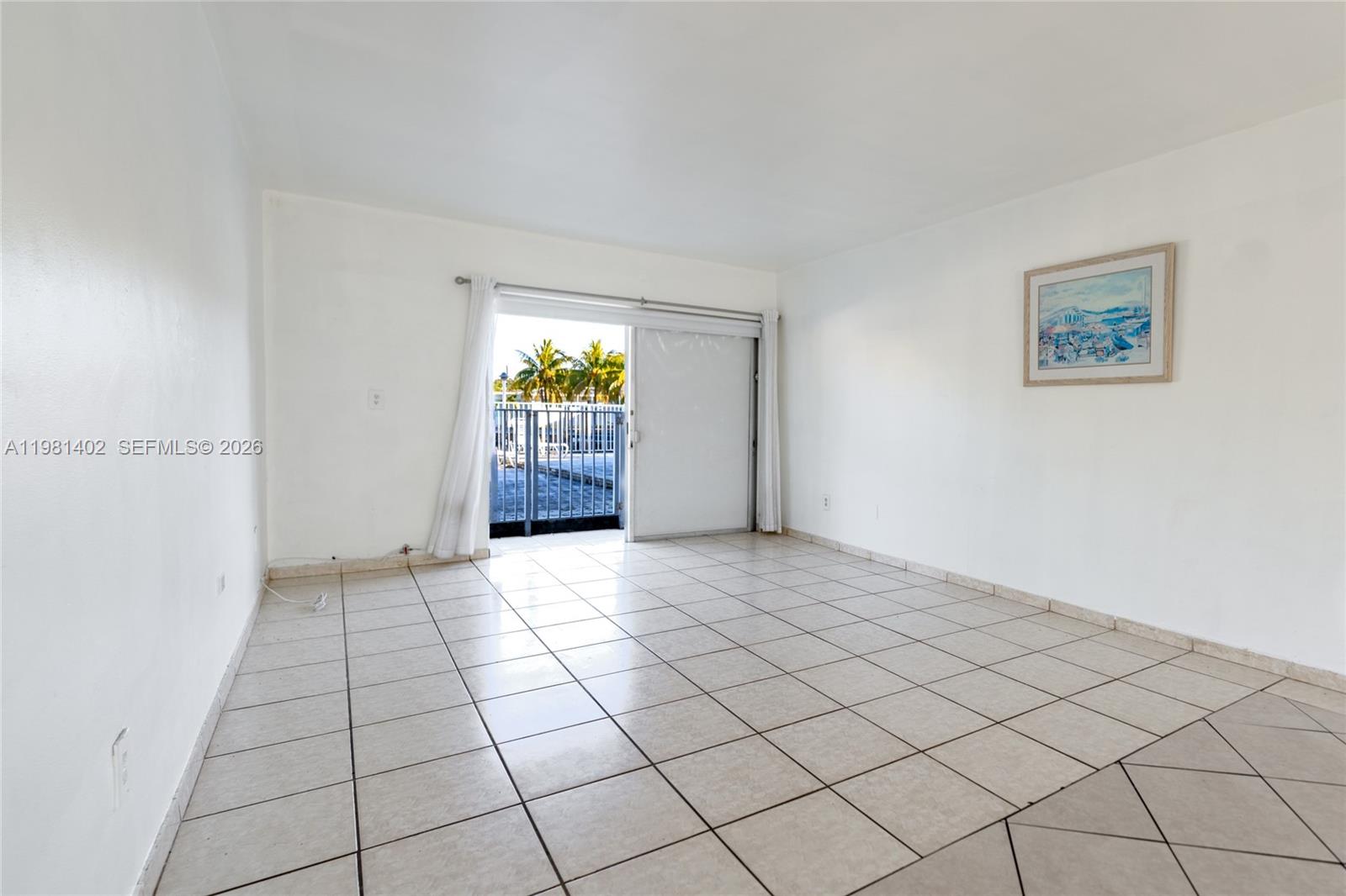 A bright living room features white walls, light-colored tile flooring, and a sliding glass door — 2225 NE 123rd St # 114, North Miami FL 33181, NORTH MIAMI, FL