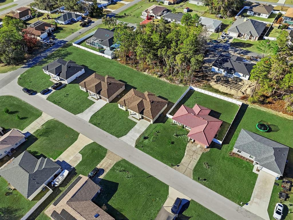 An aerial view shows three houses with driveways along a street and a fenced backyard — 4443 SW 152ND STREET, OCALA, FL