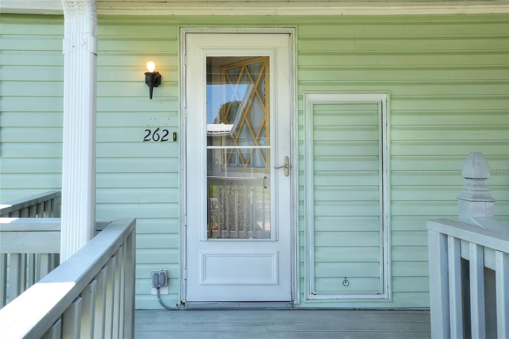 A light green house exterior features a white storm door and a small access panel — 2055 S FLORAL AVENUE UNIT 262, BARTOW, FL