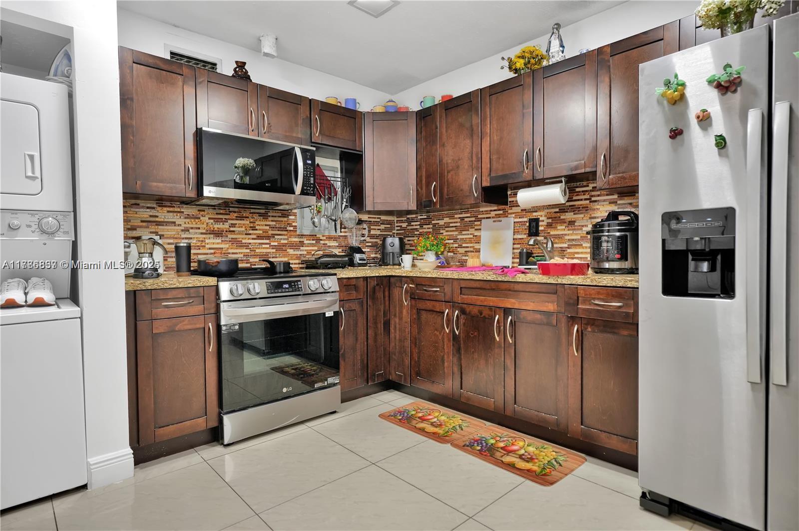 A kitchen features dark wood cabinets, stainless steel appliances, and a tiled backsplash — 7225 SW 21st St, Miami FL 33155, MIAMI, FL