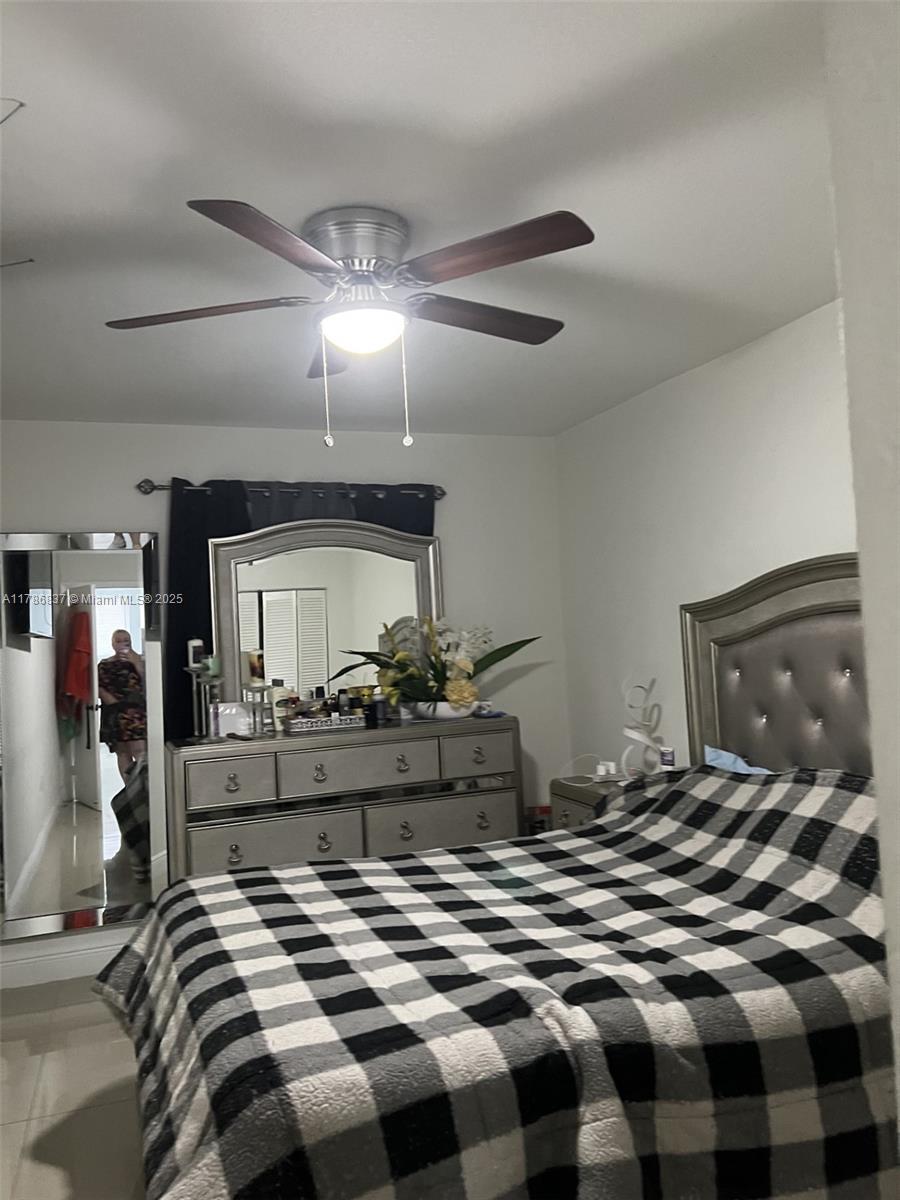 A bedroom features a bed with a plaid comforter, a dresser with a mirror, and a ceiling fan — 7225 SW 21st St, Miami FL 33155, MIAMI, FL