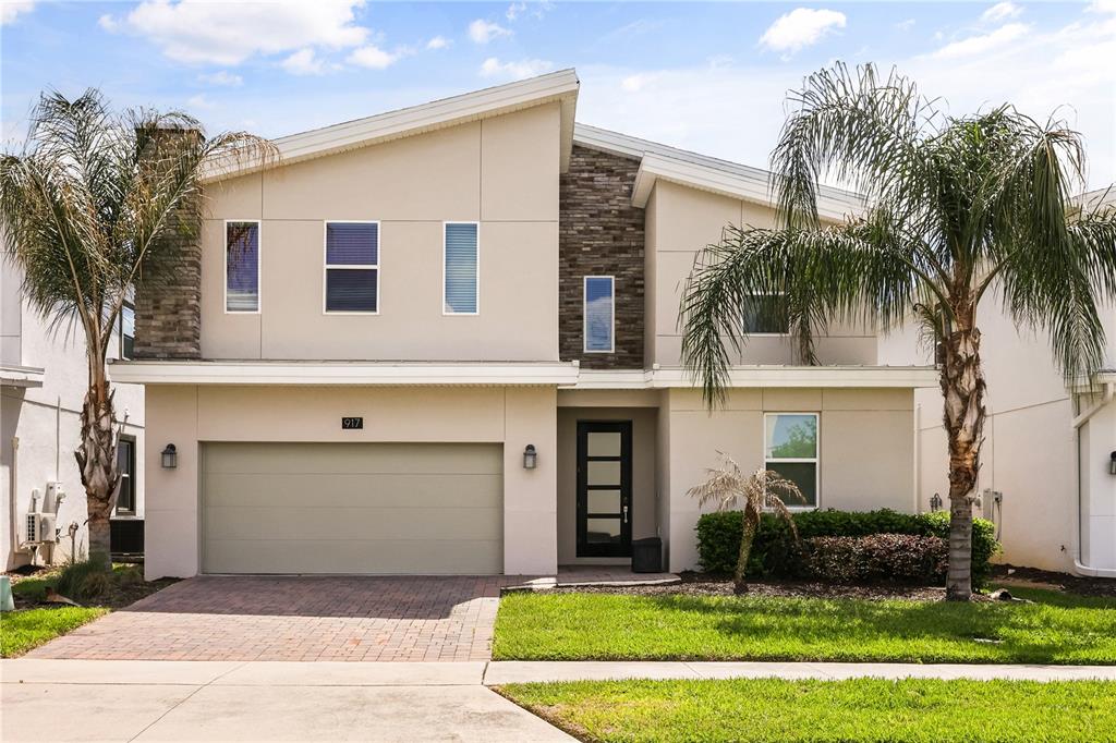 A two-story house with a beige stucco exterior, stone accents, and a two-car garage — 917 OCEAN COURSE AVENUE, DAVENPORT, FL
