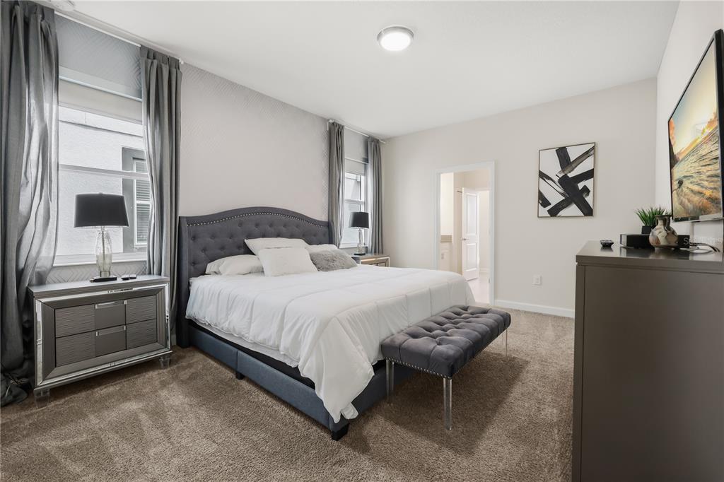 A bedroom features a tufted gray bed, mirrored nightstands, a bench, and wall-to-wall carpeting — 917 OCEAN COURSE AVENUE, DAVENPORT, FL