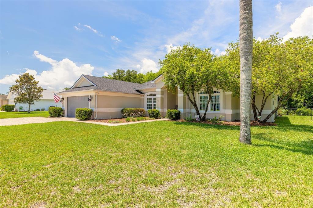 A single-story house with a two-car garage, beige stucco exterior, and a large front lawn — 43 EASTWOOD DRIVE, PALM COAST, FL