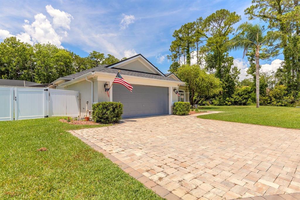 A house exterior features a gray garage door, a paved driveway, and an American flag — 43 EASTWOOD DRIVE, PALM COAST, FL