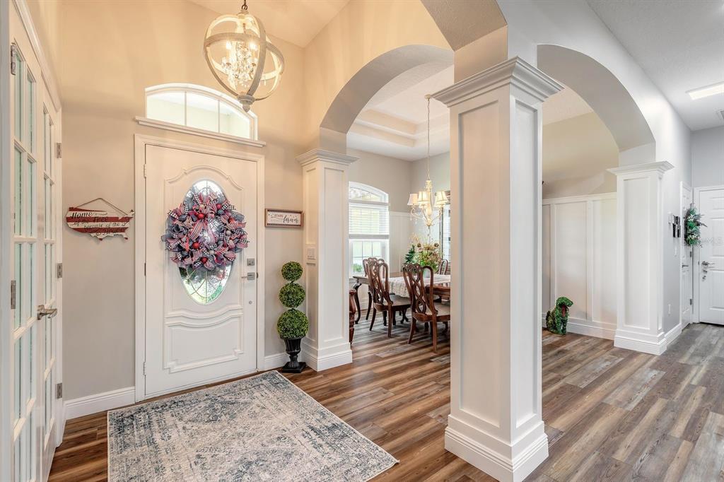 A bright entryway features wood-look flooring, white columns, arched transitions, and a dining room beyond — 43 EASTWOOD DRIVE, PALM COAST, FL