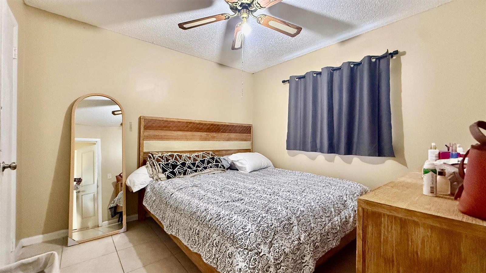 A bedroom features a bed with a patterned comforter, a wooden headboard, and a floor mirror — 134 Jennings Avenue # 134, FL 33463, FL