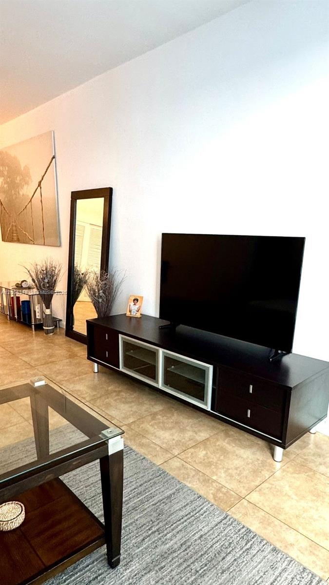 A living room features a dark wood media console, a television, and a floor mirror — 4001 S Ocean Dr, Hollywood FL 33019, HOLLYWOOD, FL