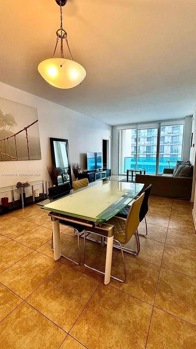 A dining area with a glass table and tile flooring leads to a living room balcony — 4001 S Ocean Dr, Hollywood FL 33019, HOLLYWOOD, FL