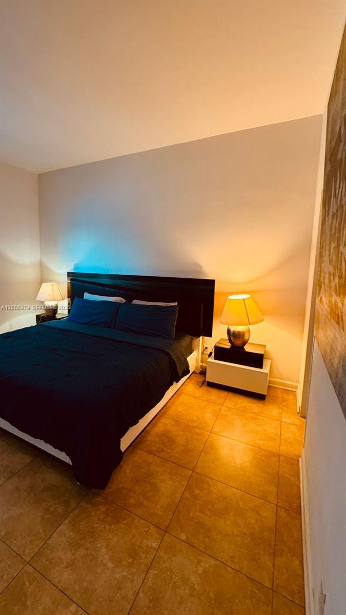 A bedroom features a dark bed frame, dark bedding, and two bedside lamps on stands — 4001 S Ocean Dr, Hollywood FL 33019, HOLLYWOOD, FL