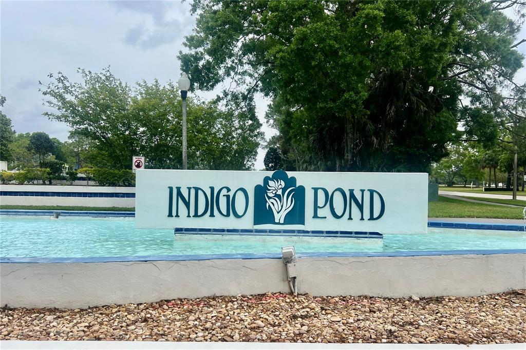 A sign for Indigo Pond sits in front of a small pond with a fountain — 3629 INDIGO POND DRIVE UNIT 3629, PALM HARBOR, FL