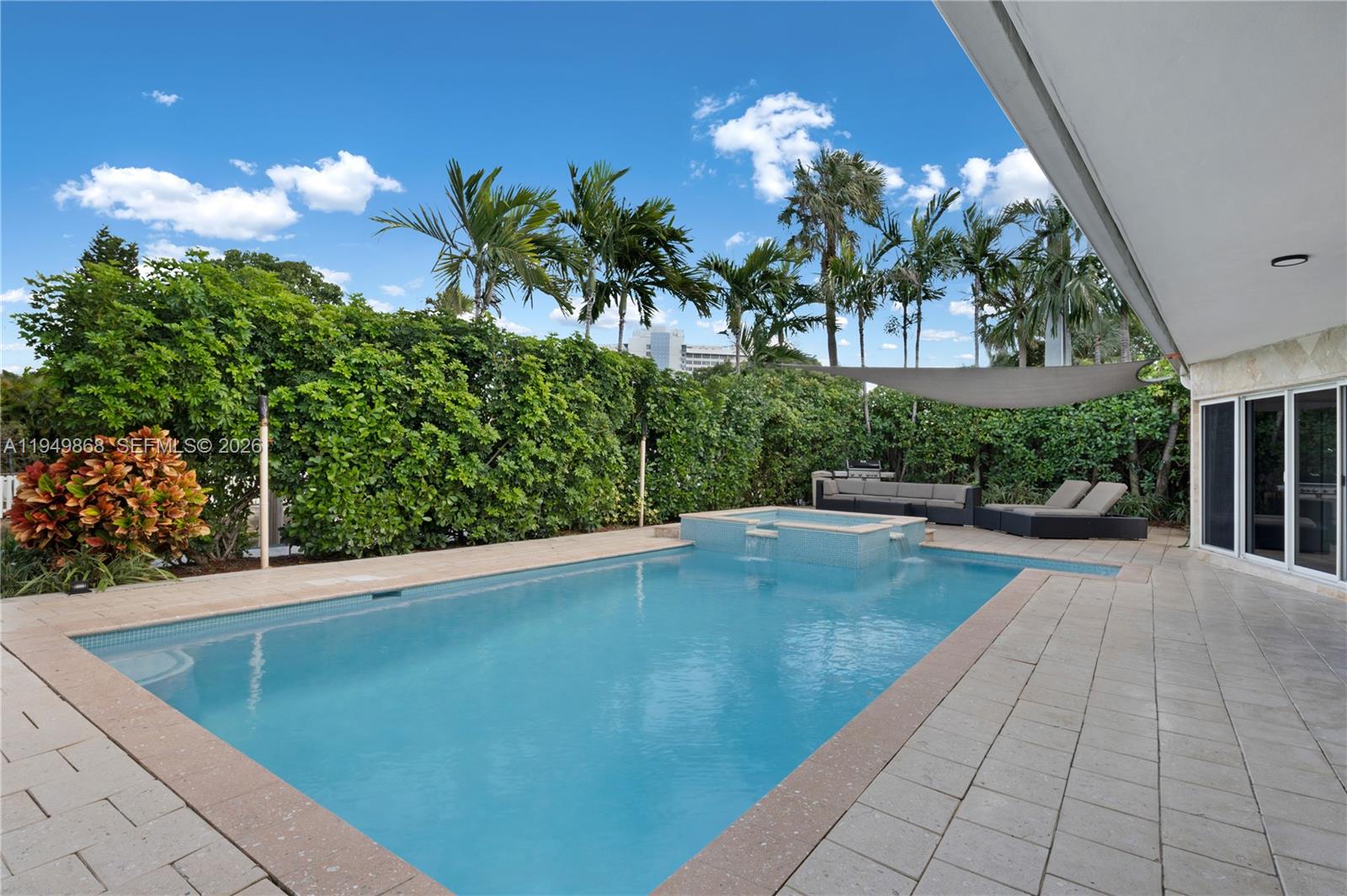 A rectangular swimming pool with an attached spa sits on a tiled patio outdoors — 1155 S Biscayne Point Rd, Miami Beach FL 33141, MIAMI BEACH, FL