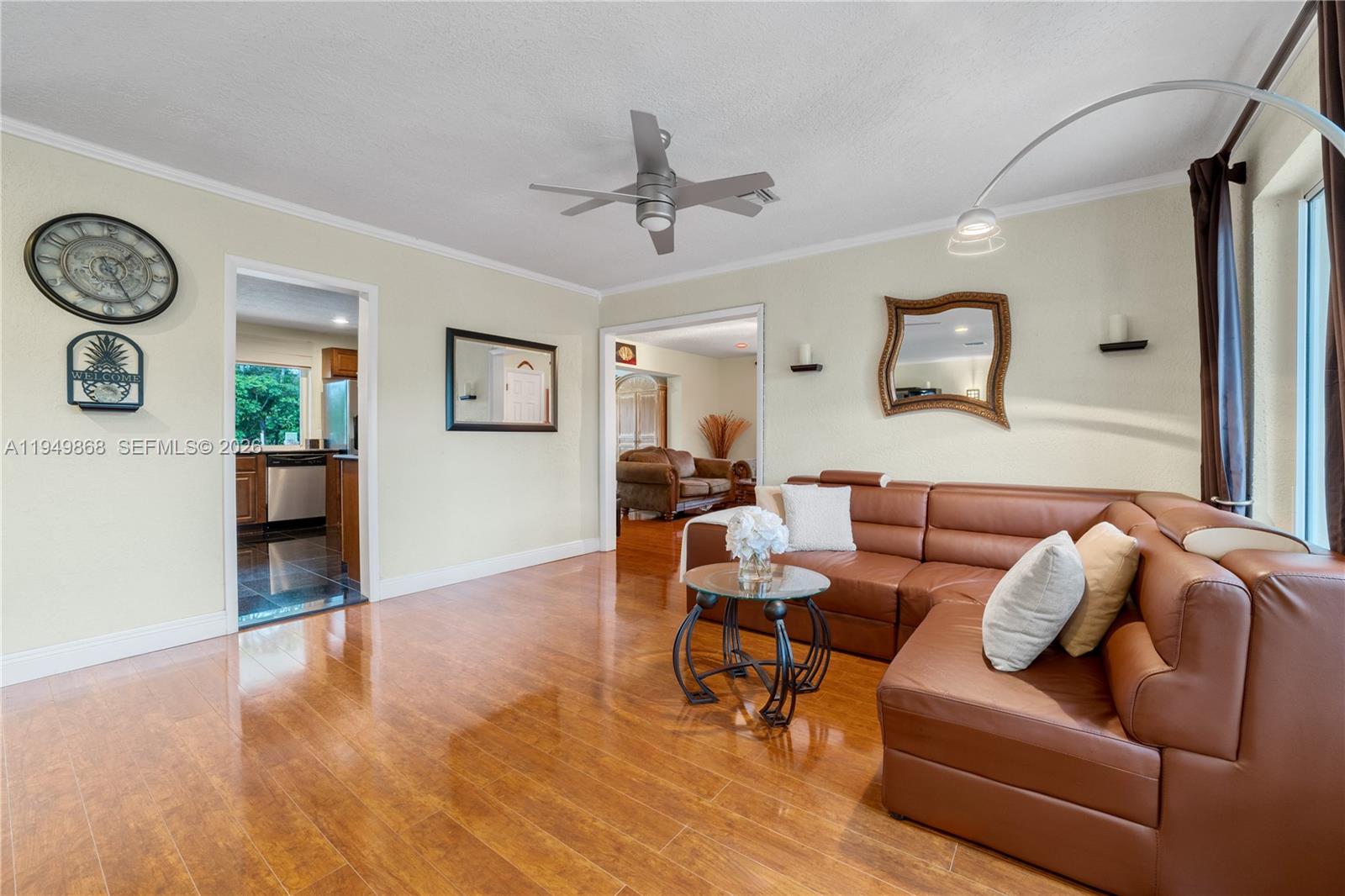 A living room features a brown leather sectional, hardwood floors, and a ceiling fan — 1155 S Biscayne Point Rd, Miami Beach FL 33141, MIAMI BEACH, FL