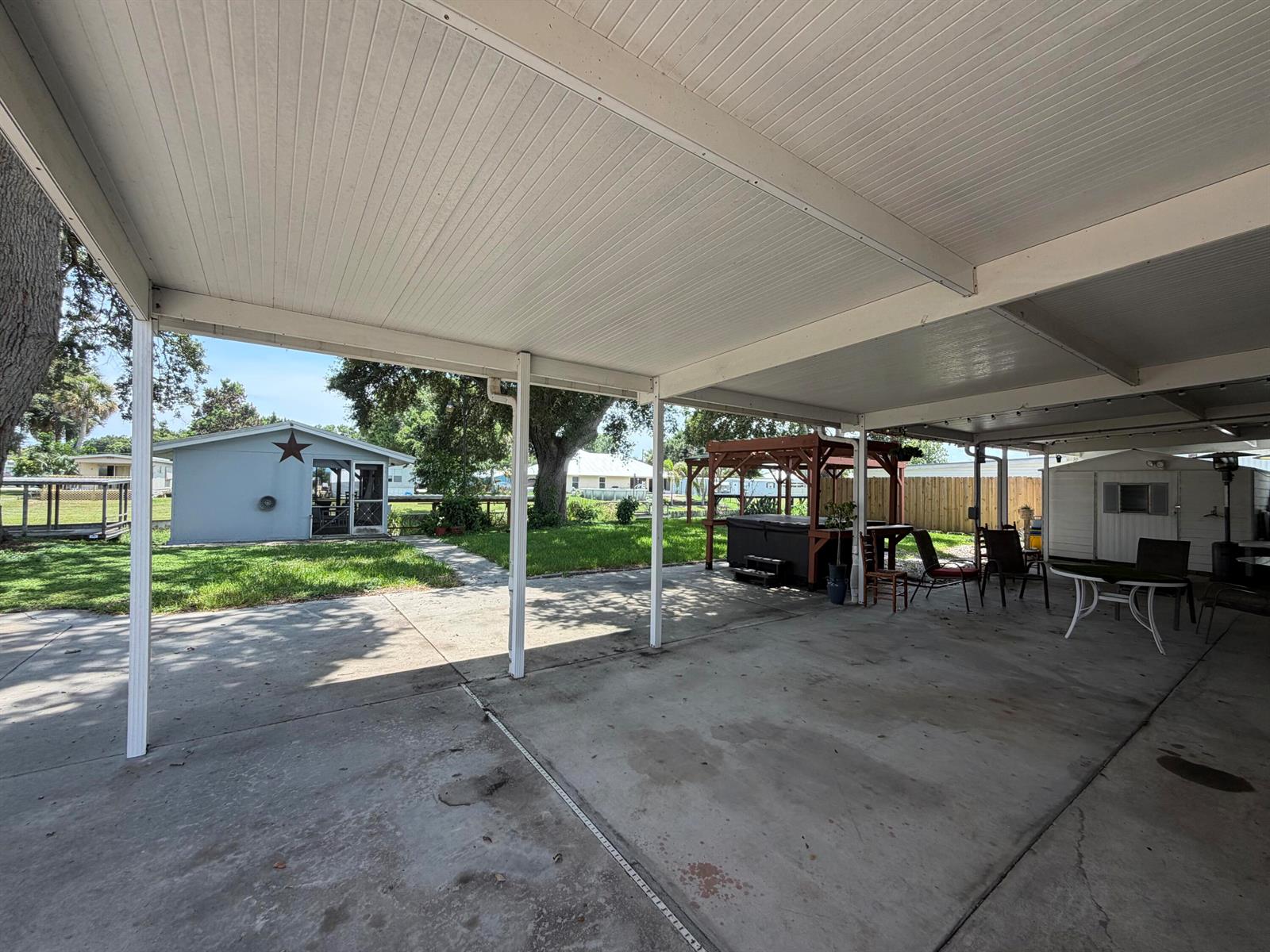 A large concrete carport features a covered patio area with a hot tub and furniture — 3212 SE 24th Street, Okeechobee FL 34974, OKEECHOBEE, FL