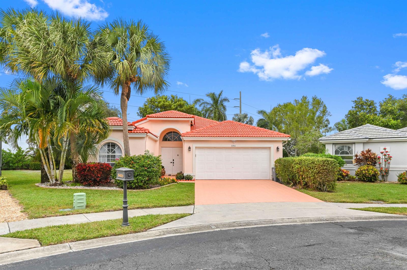 A peach-colored house with a red tile roof and a two-car garage sits on a lawn — 6451 Tiara Drive, Boynton Beach FL 33437, BOYNTON BEACH, FL