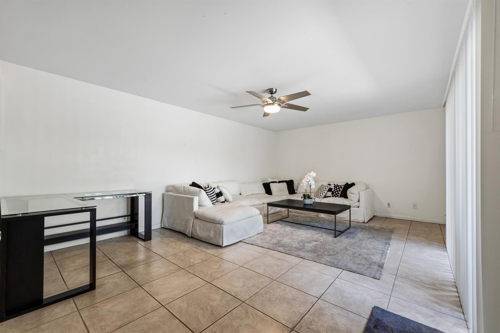 A living room features a white sectional sofa, a black coffee table, and tile flooring — 3852 Jefferson Street, Stuart FL 34997, STUART, FL