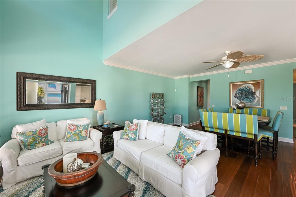 A living and dining area features teal walls, white sofas, and dark wood flooring — 109 6TH STREET N UNIT A, BRADENTON BEACH, FL