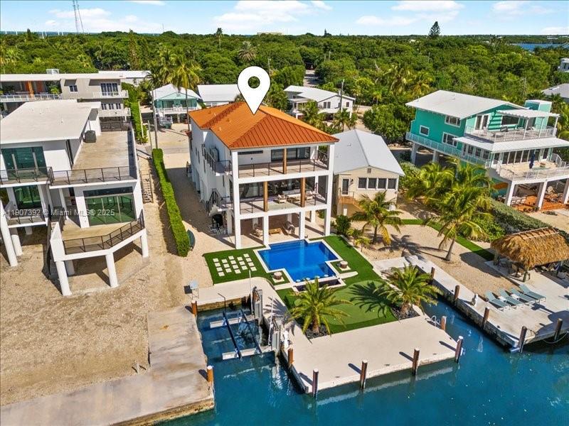 An aerial view shows a multi-story waterfront house with a pool, dock, and boat lift — 239 Tavernier Dr, Tavernier FL 33070, TAVERNIER, FL
