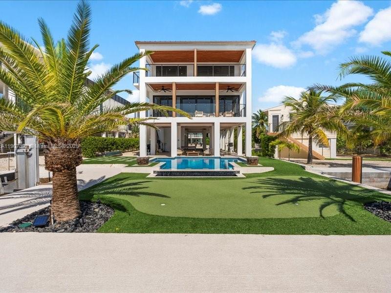 A three-story house with a backyard pool and putting green under a blue sky — 239 Tavernier Dr, Tavernier FL 33070, TAVERNIER, FL