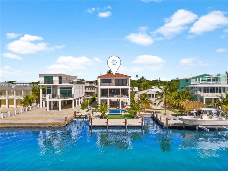 A waterfront house with a pool and dock sits between two other coastal homes — 239 Tavernier Dr, Tavernier FL 33070, TAVERNIER, FL