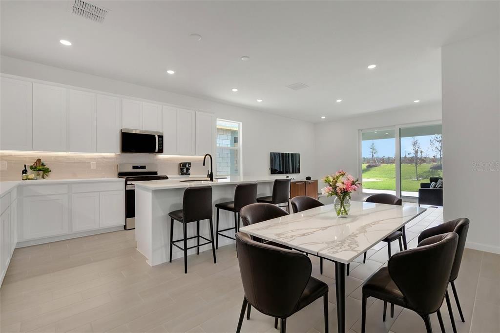 A modern kitchen and dining area with white cabinetry, a marble-topped table, and sliding doors — 5412 NW CAMBERLY COURT, PORT ST LUCIE, FL