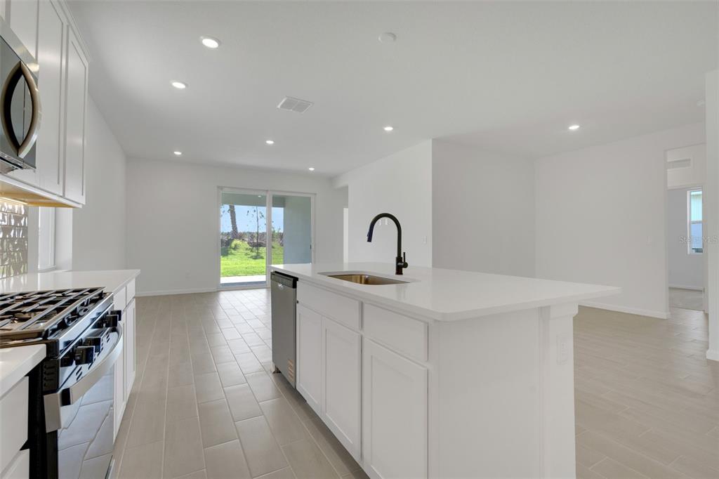 A modern kitchen with white cabinets, a central island, and light tile flooring — 5412 NW CAMBERLY COURT, PORT ST LUCIE, FL
