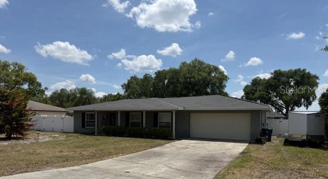 A single-story house with a gray roof, brick exterior, and a concrete driveway — 1104 YARNELL AVENUE, LAKE WALES, FL