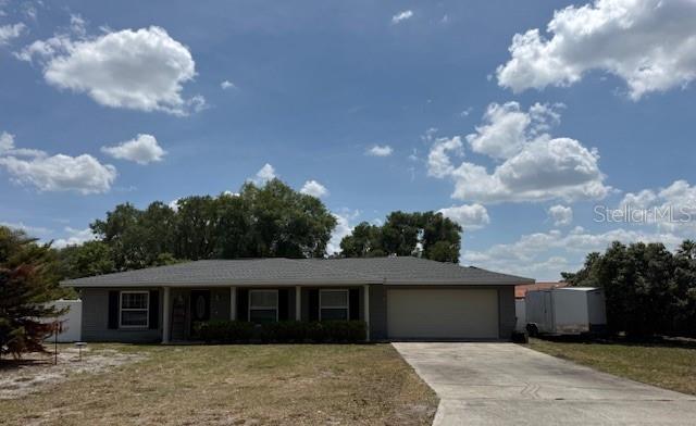 A single-story house with a gray roof, light-colored siding, and a concrete driveway — 1104 YARNELL AVENUE, LAKE WALES, FL