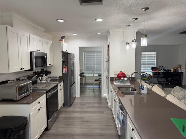 A kitchen features white cabinetry, stainless steel appliances, a breakfast bar, and light wood flooring — 1104 YARNELL AVENUE, LAKE WALES, FL