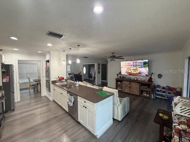 An open-concept kitchen and living area features white cabinetry, a large island, and wood-look flooring — 1104 YARNELL AVENUE, LAKE WALES, FL