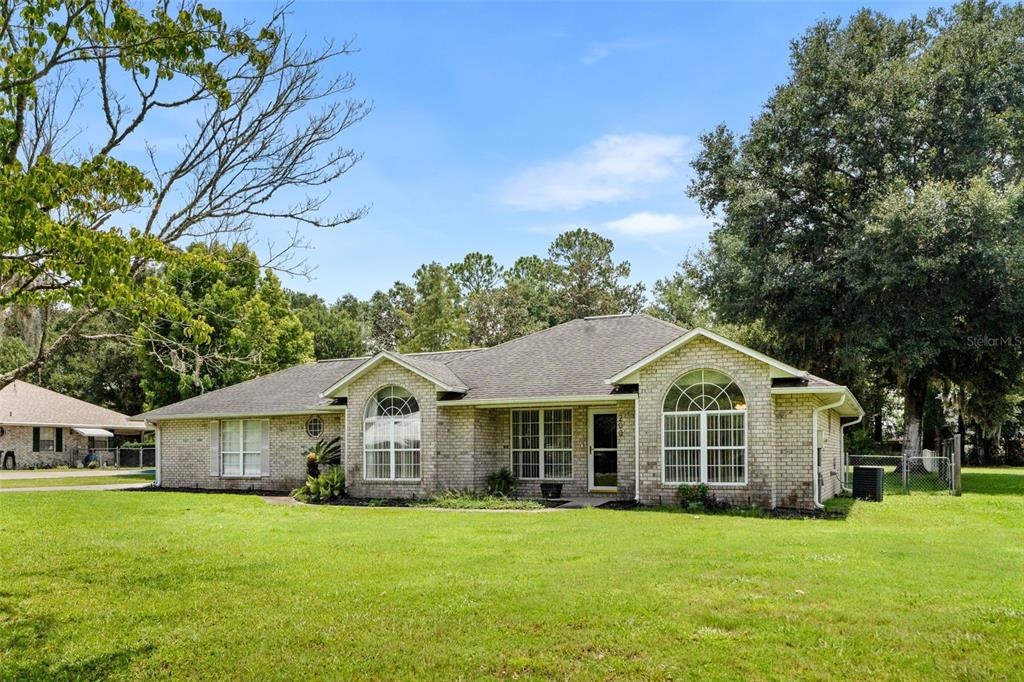 A single-story brick house with a hip roof and two arched windows sits on a lawn — 200 NW CHARLOTTE GLEN, LAKE CITY, FL