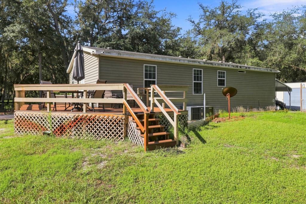 A single-story house with tan siding features a wooden deck and lattice skirting — 3970 SW 45TH AVENUE, BUSHNELL, FL
