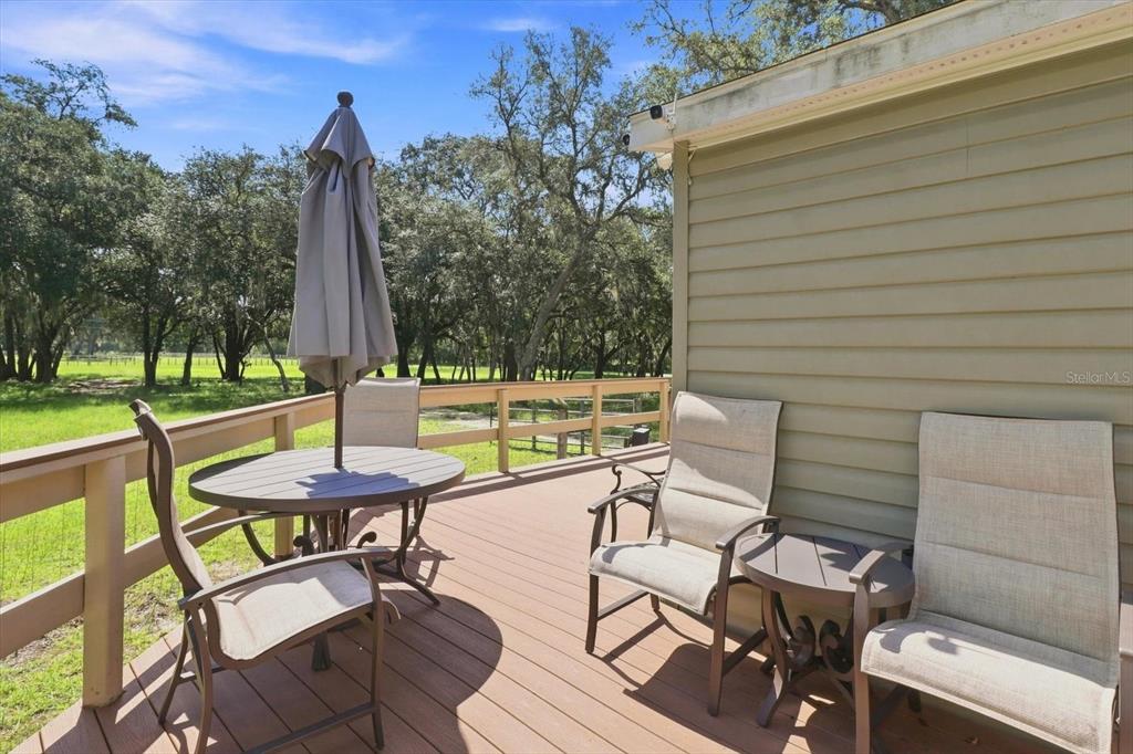 A wooden deck features a patio table with an umbrella and several outdoor chairs — 3970 SW 45TH AVENUE, BUSHNELL, FL
