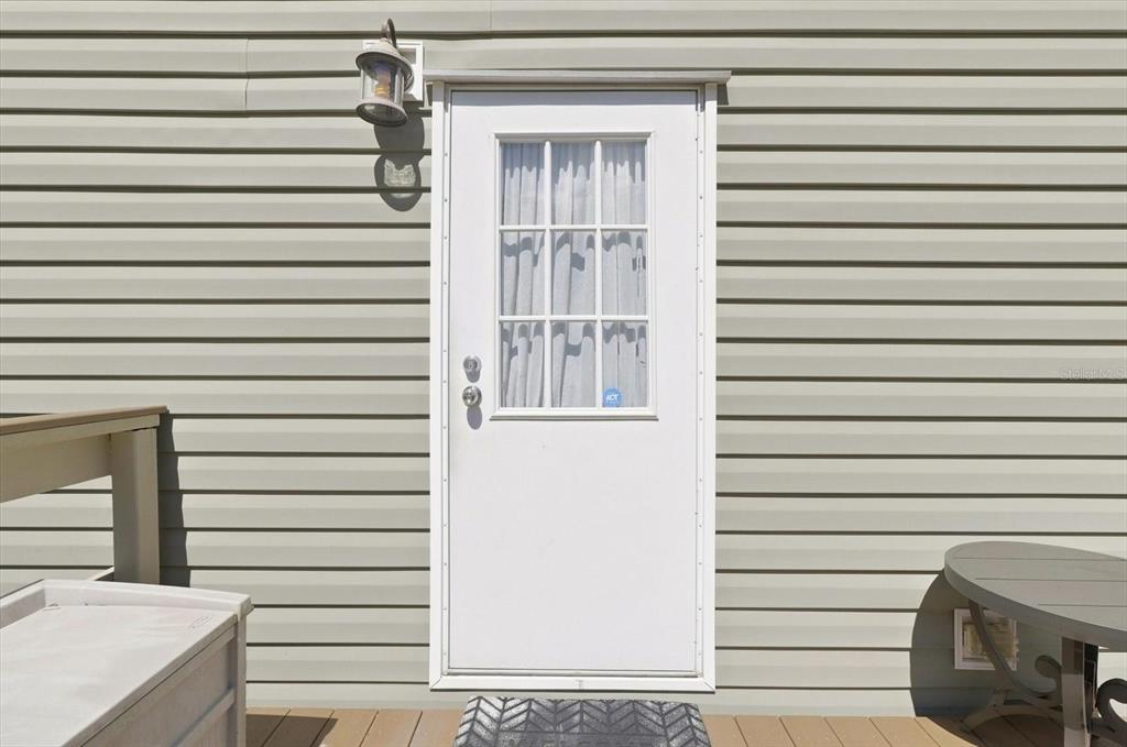 A white door with a window sits on a deck against light-colored horizontal siding — 3970 SW 45TH AVENUE, BUSHNELL, FL