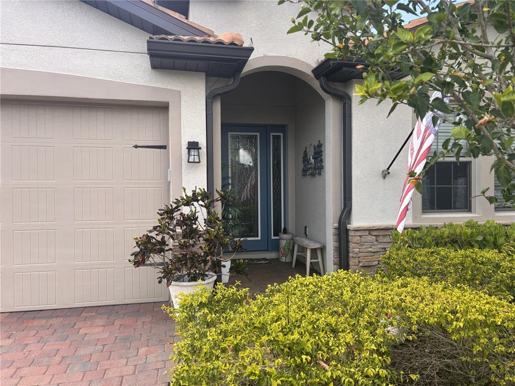The exterior of a house features a beige garage door, a covered entryway, and landscaping — 288 TOSCAVILLA BOULEVARD, NOKOMIS, FL