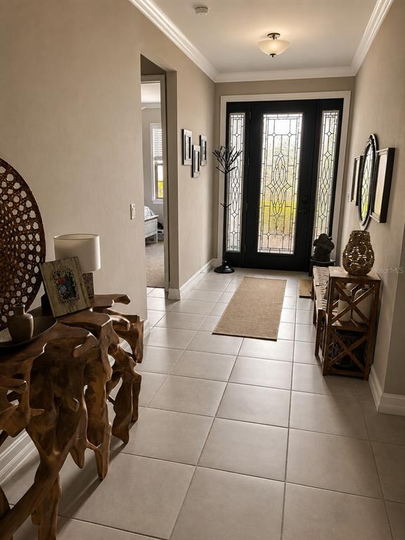 A tiled entryway features a wooden console table, a coat rack, and a glass-paneled front door — 288 TOSCAVILLA BOULEVARD, NOKOMIS, FL